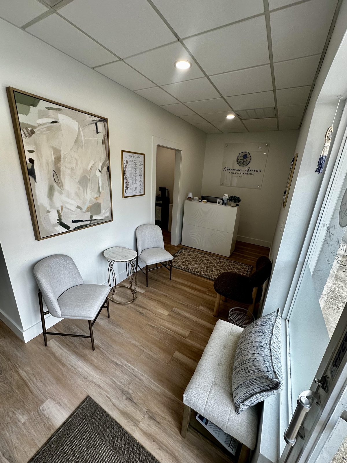 The reception desk, with the practice logo on a frosted glass panel above it, chairs and a large abstract canvas to one side, and a rug on wood flooring